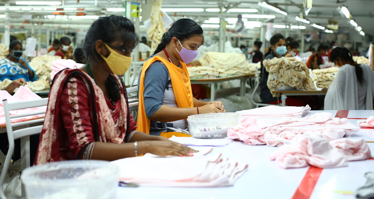 Zwei Frauen in einer Textilfabrik in Indien bei der Arbeit. 